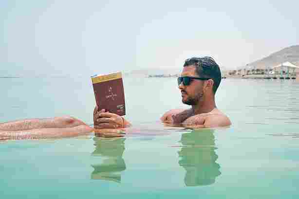 Man reading a book while swimming