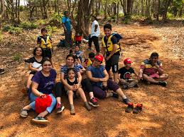 Pugmarks camp - a group of kids with their guide sitting on forest ground during camping