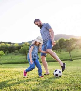 a dad and a kid playing football on a green field