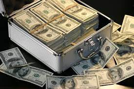 a box full of money in dollars with a black background, with money strewn around the box as well.