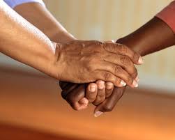 Two individuals clasping hands in a room.