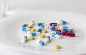 A white plate with pills and a glass of water, essential for medication intake.