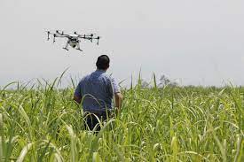 A man standing in a field with a drone, capturing aerial views.