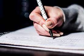 A person writing on a notebook with a pen, capturing thoughts and ideas on paper.