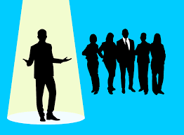A man standing before a group of business people, depicted as a silhouette.
