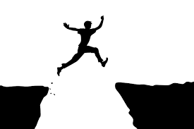 A daring man leaps over a cliff, displaying courage and fearlessness in his thrilling adventure.