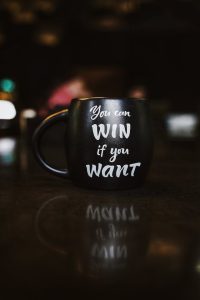 A white ceramic mug with the text "You win it, you want it" written in bold black letters.