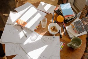 A cluttered table with papers, pens, and coffee cups, creating a busy and productive workspace.