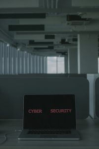 A laptop with "cyber security" written on it, placed on a desk.