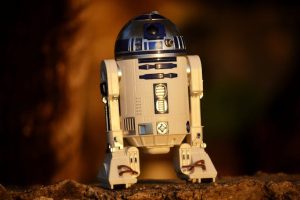A Star Wars R2D2 toy sitting on a rock, showcasing the iconic character from the popular sci-fi franchise.