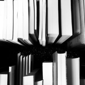 Black and white photo showing books arranged on a shelf.