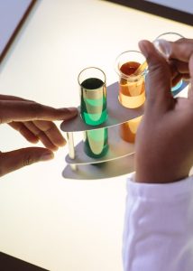  Image of a tray held by a person with three different colored liquid containers.