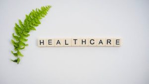 Scrabble board with the word "healthcare" spelled out, surrounded by a fern.