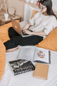 A woman sitting on a bed with a laptop, engrossed in her work.