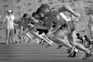 Men running on a track in a black and white photo.