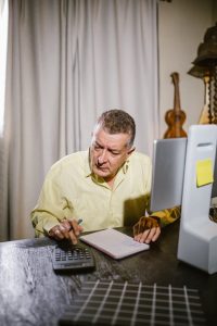 A man sitting at a desk with a computer and a pen.