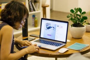 A woman sitting at a table with a laptop, working on her computer.